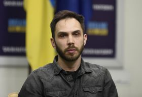 young man in a dark-grey shirt, Ukrainian flag on the background